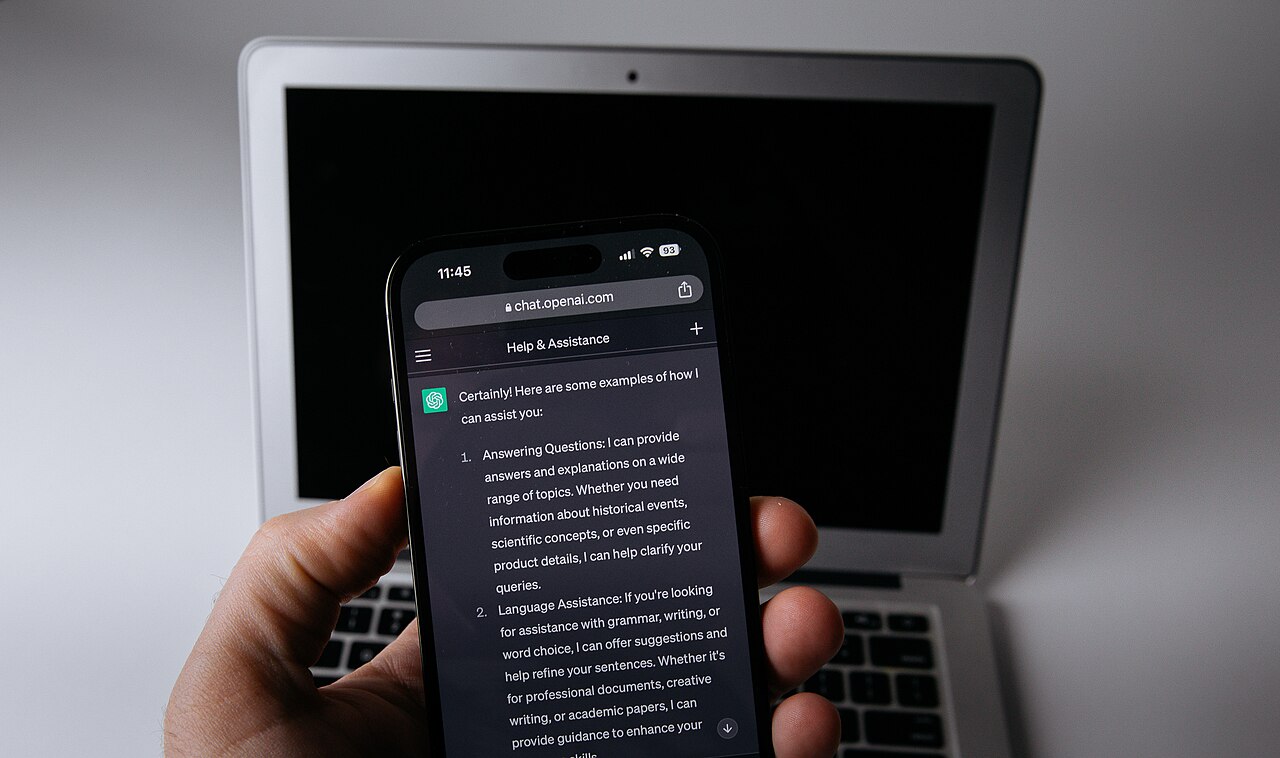 Móvil con la app de ChatGPT junto a un portátil